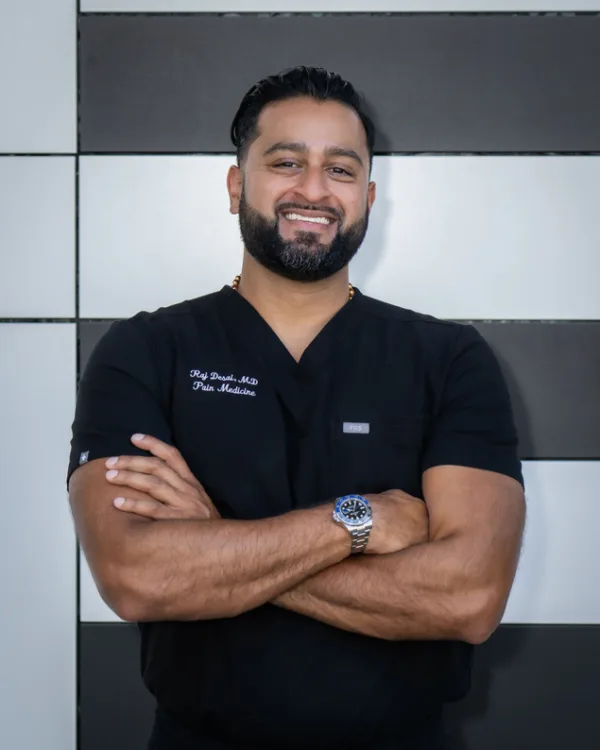 Dr. Raj Desai in black scrubs, smiling with arms crossed